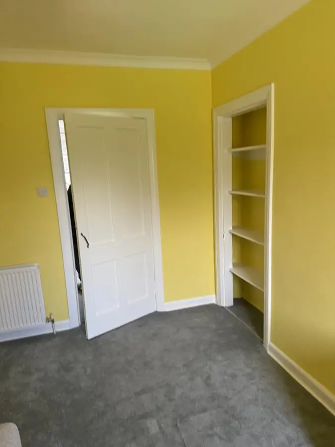 Bedroom repainted bright yellow with white doors and built-in shelving
