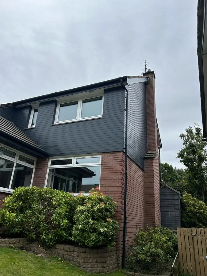 Semi-detached house with dark painted cladding on the upper storey
