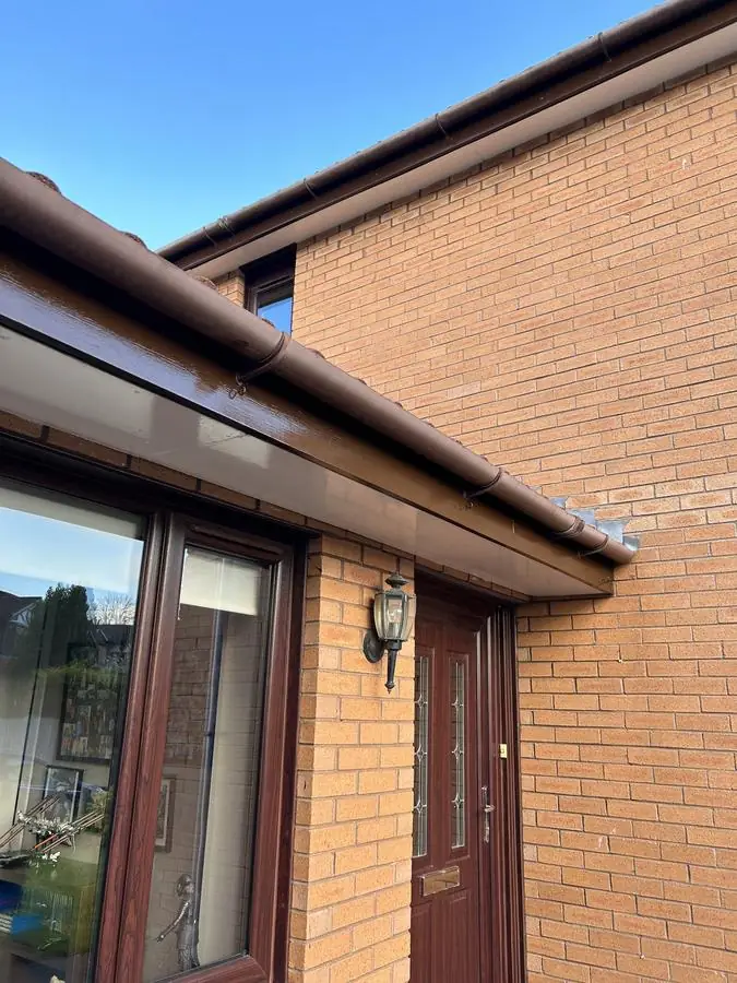 Close view of a repainted dark brown fascia and white soffit on a brick house