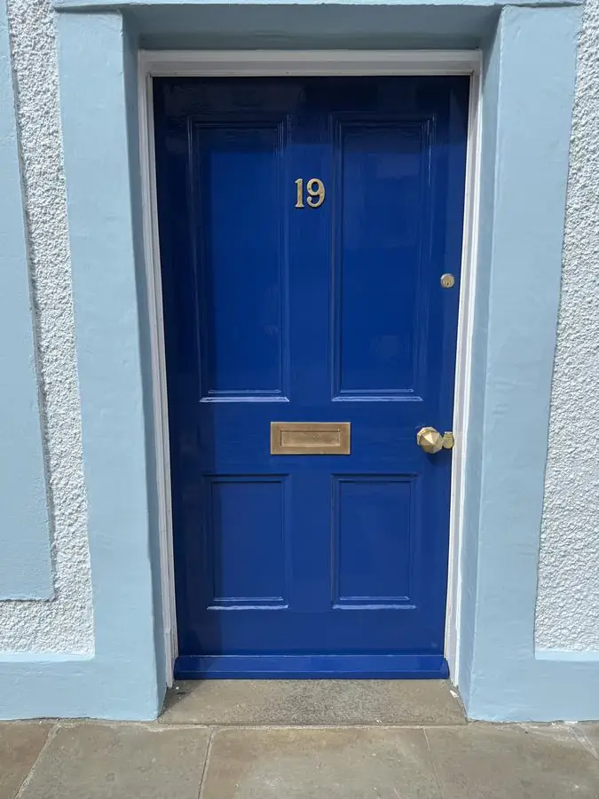 Panelled front door with a deep, high-gloss painted finish and brass letterbox