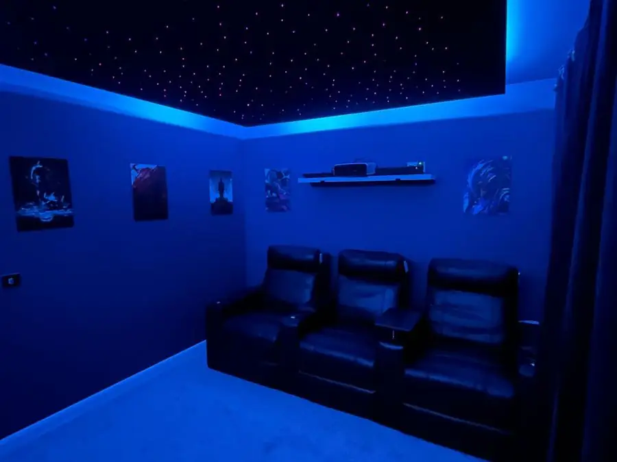 Home cinema room with dark walls, a star-effect ceiling and recliner seating