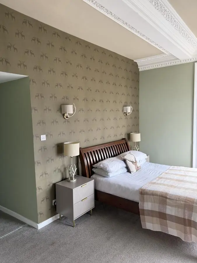 Hotel bedroom with a patterned feature wallpaper behind the bed