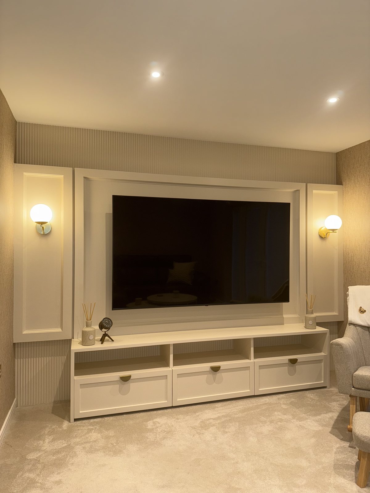 Living room media wall with panelled surrounds, fluted panelling and built-in cream units