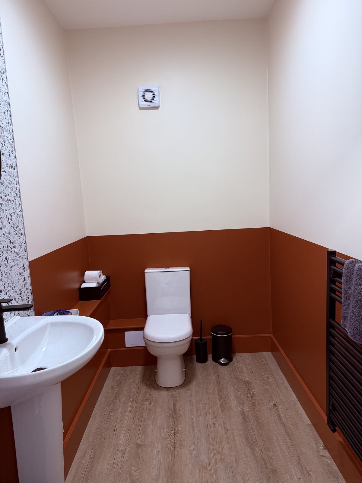 Office WC with terracotta lower walls and skirting beneath cream upper walls