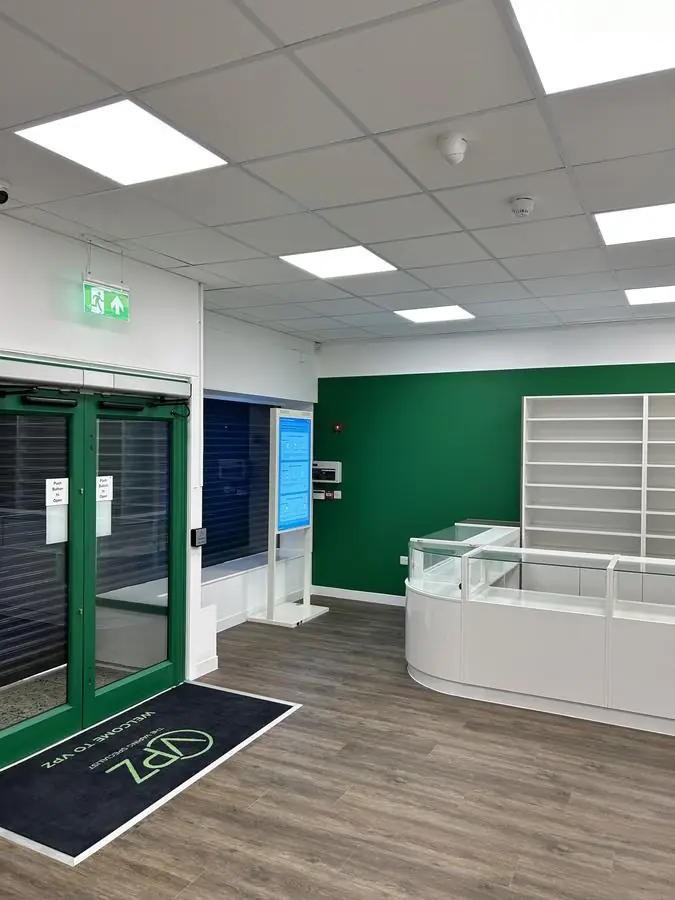 Retail shop floor with white walls and a deep green feature wall