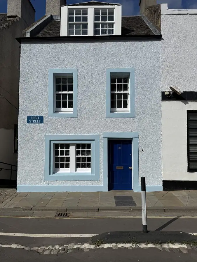 Terraced townhouse frontage repainted in pale render with contrasting window and door surrounds