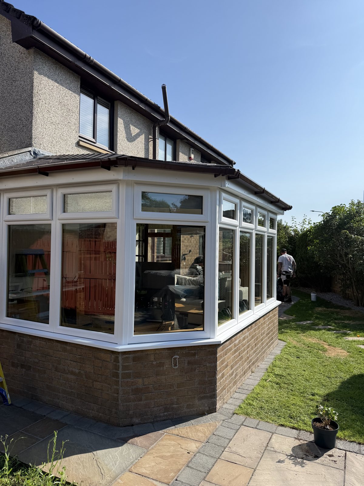 White UPVC conservatory frames and dark brown roof trim at the corner of a house