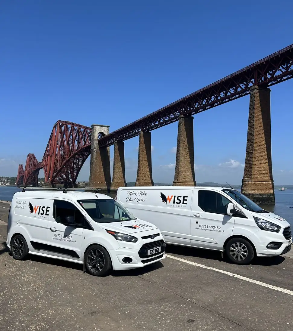 Two white Wise Decor vans parked in front of the Forth Bridge